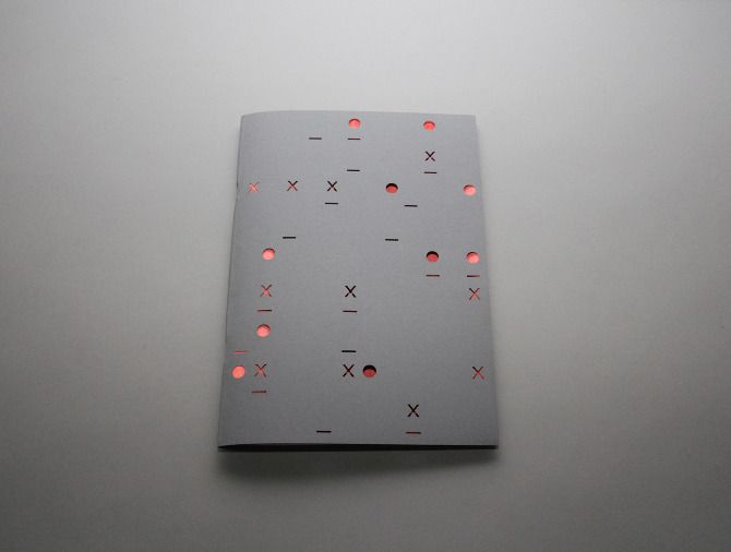 A grey paper booklet on a desk, a network punched through it, glowing coral from the inside.