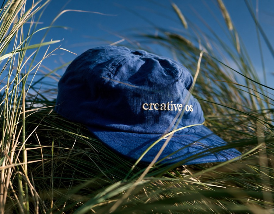 A cap embroidered creative os, lying in dune grass