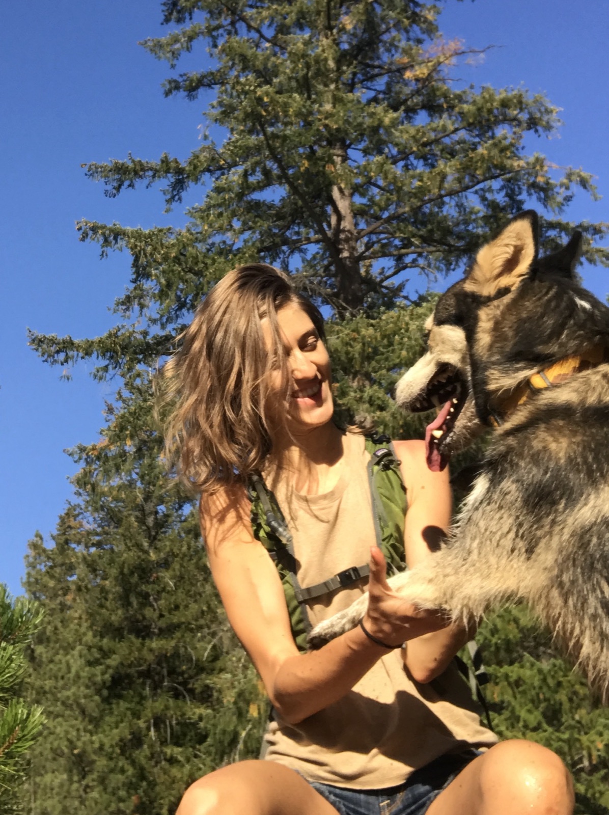 Ivy laughing with her husky Maca on a sunny hike